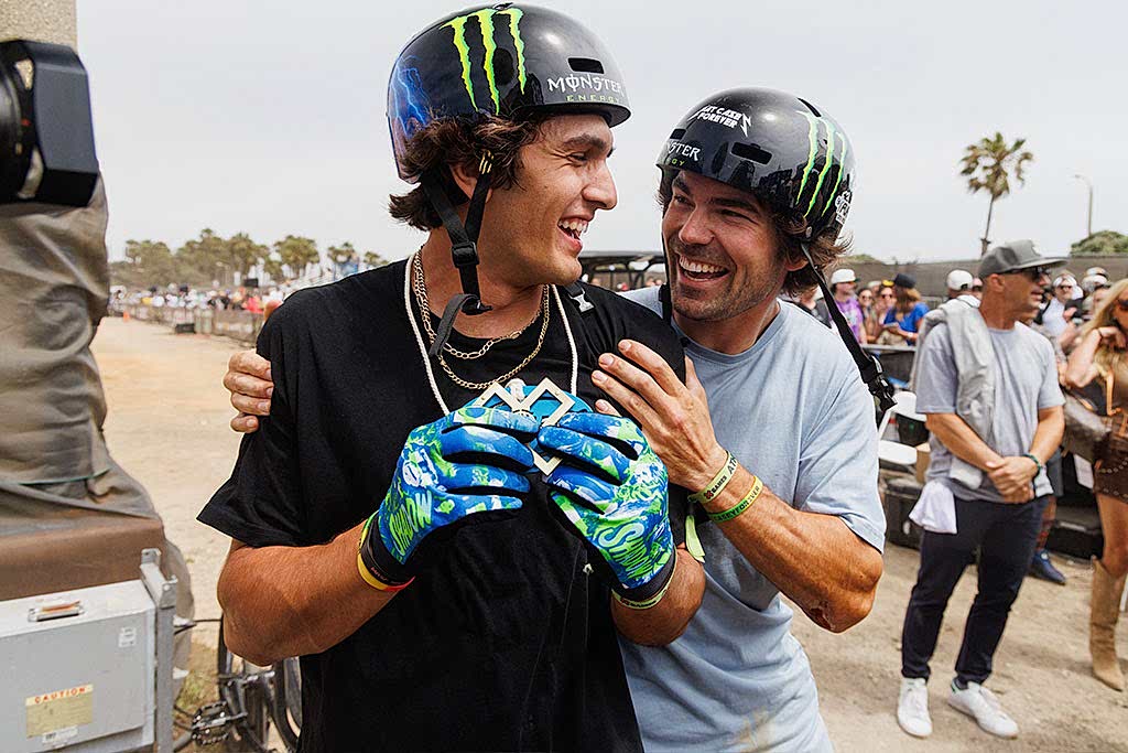 two X Games athletes wearing Monster Energy helmets celebrating together after a competition